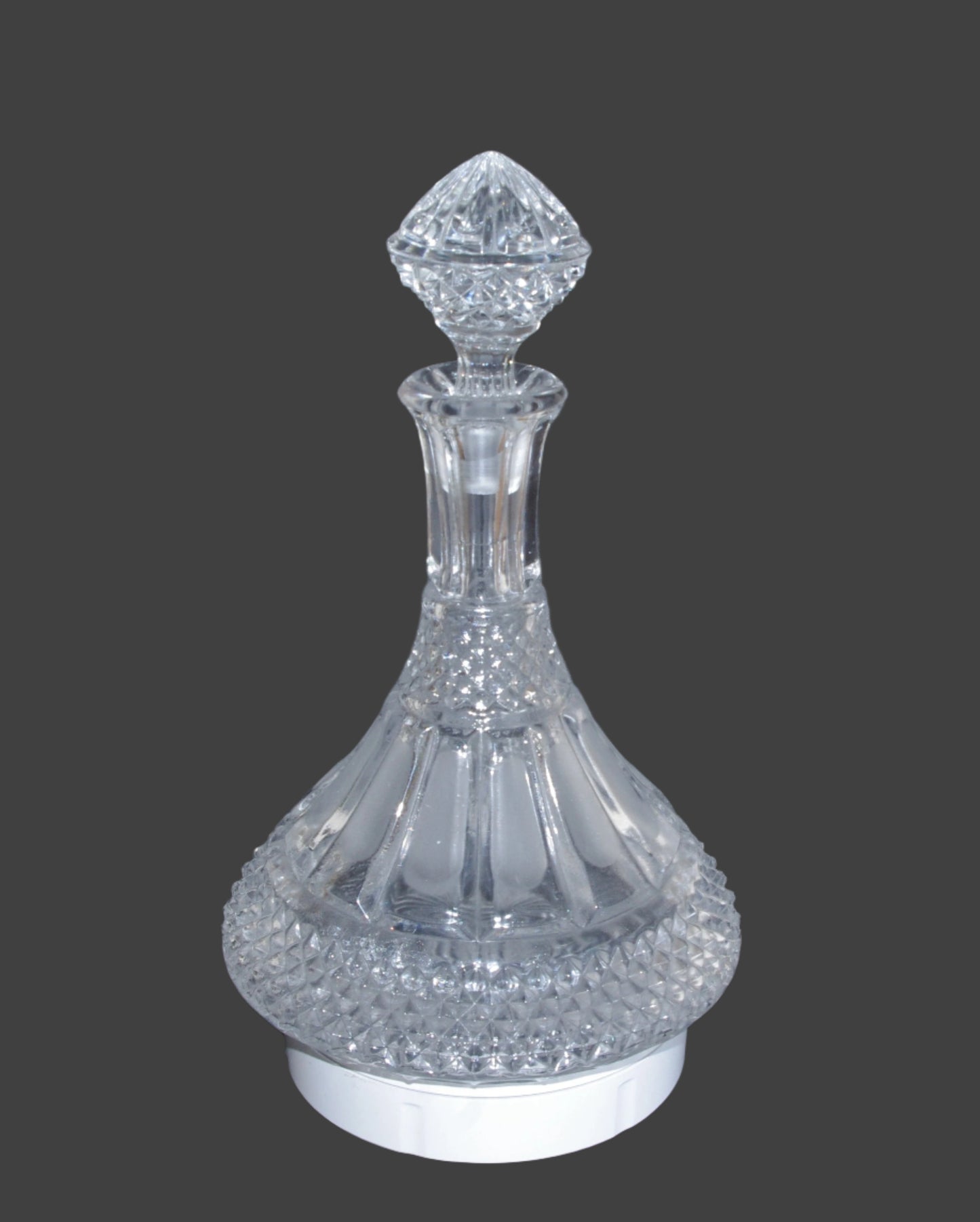 Clear crystal Wine or Port decanter with intricate design on a dark background
