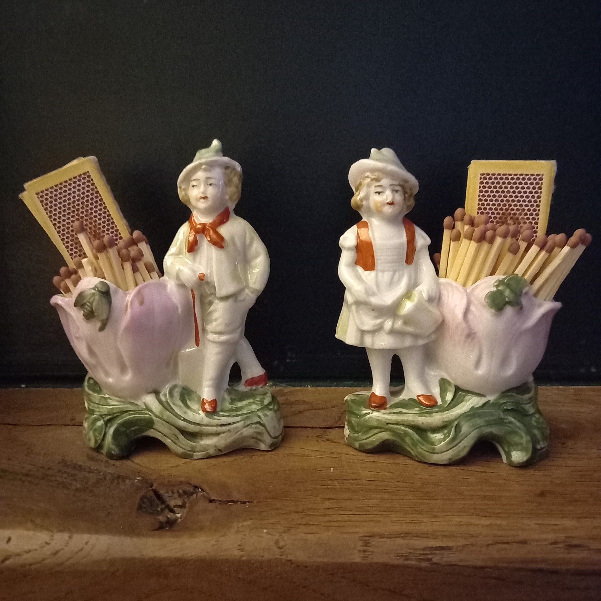 Pair of antique German porcelain spill vases with boy and girl figures beside pink tulip-shaped holders, used as decorative match storage, circa 1900 figural ceramic mantel decor
