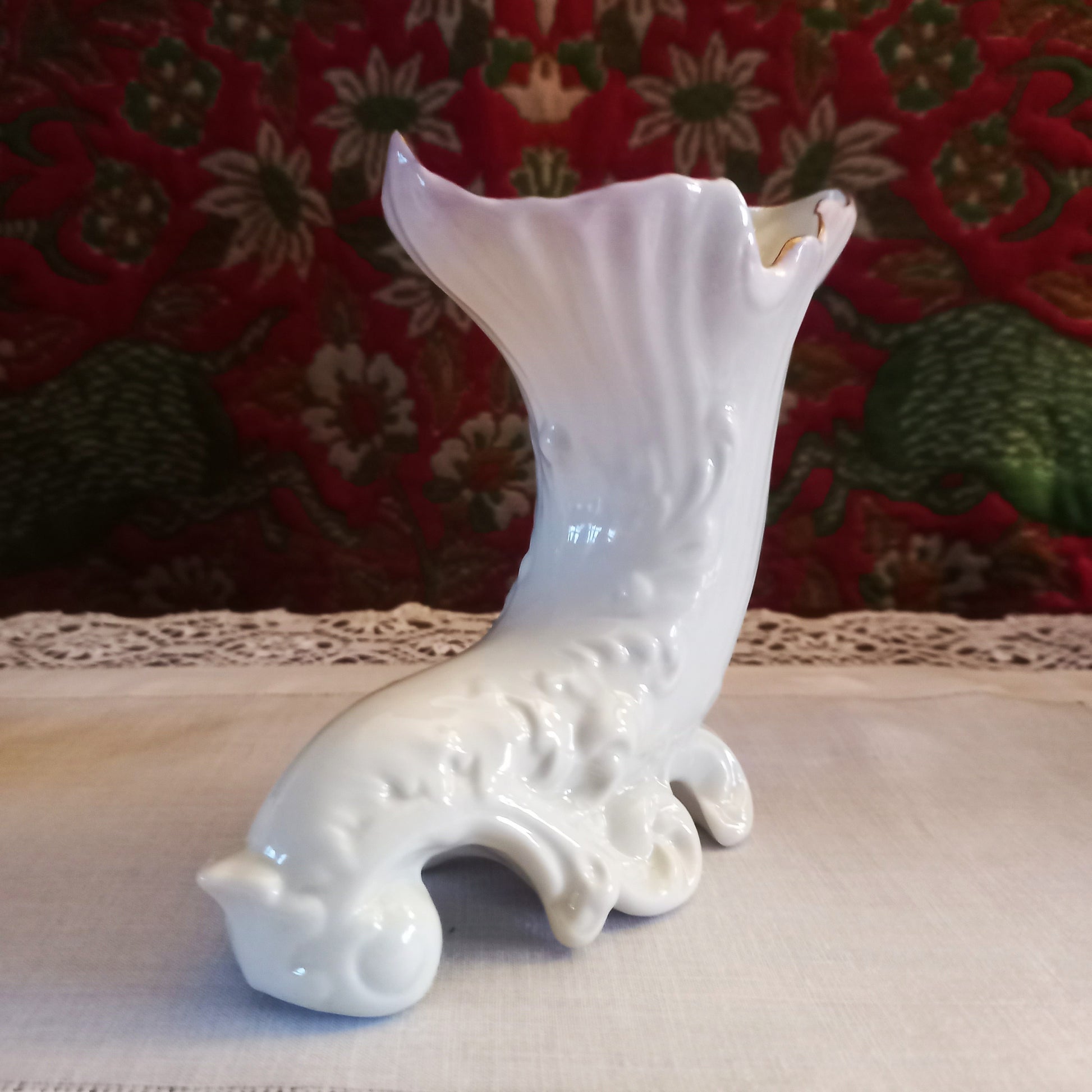 A single collectible Belleek spill vases in parian porcelain, buffet and tapestry , is shown in side view, empty revealing the delicate fluted rim and scrolled feet
