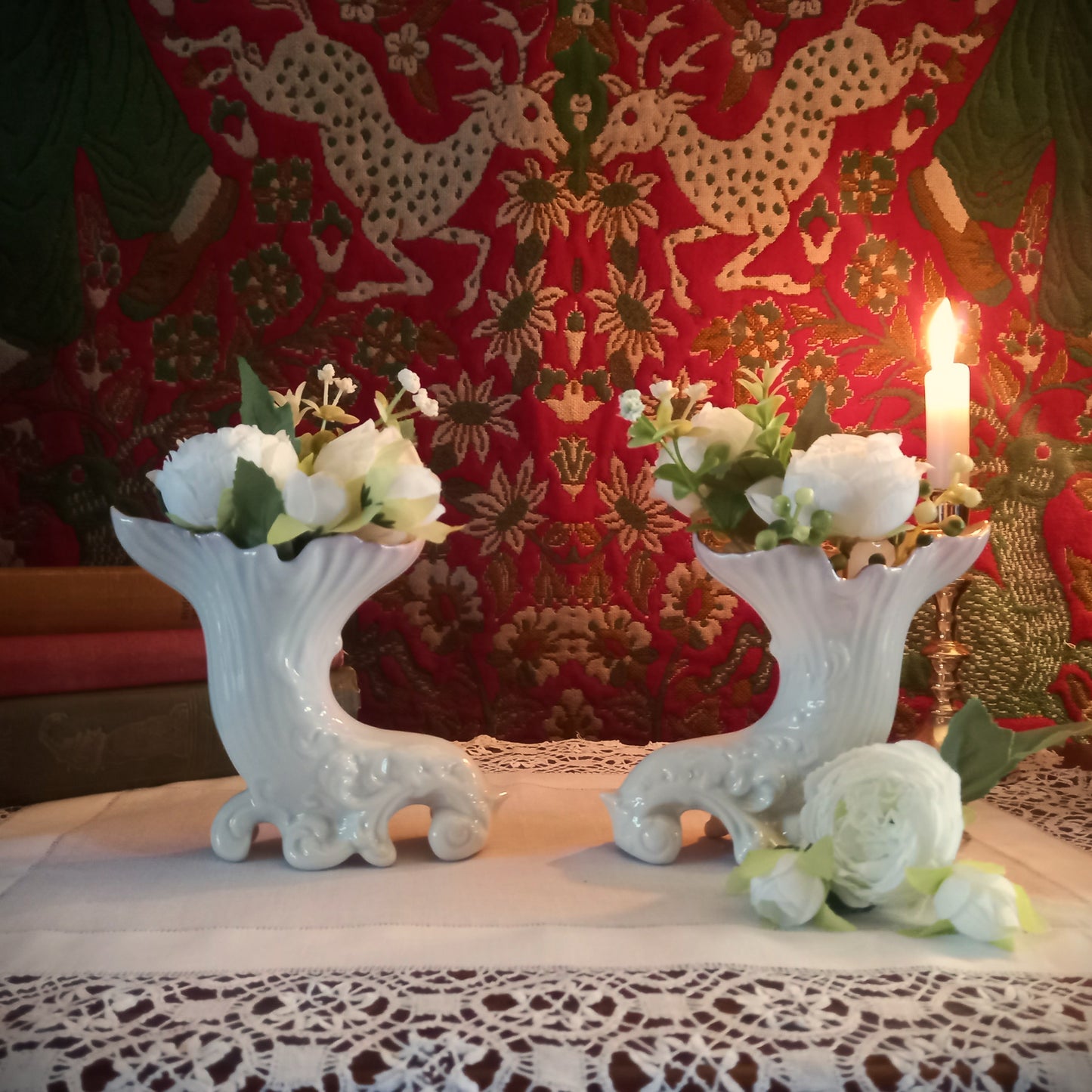 A pair of collectible Belleek spill vases in parian porcelain, buffet and tapestry with delivate peony flower display  is shown in an antique setting