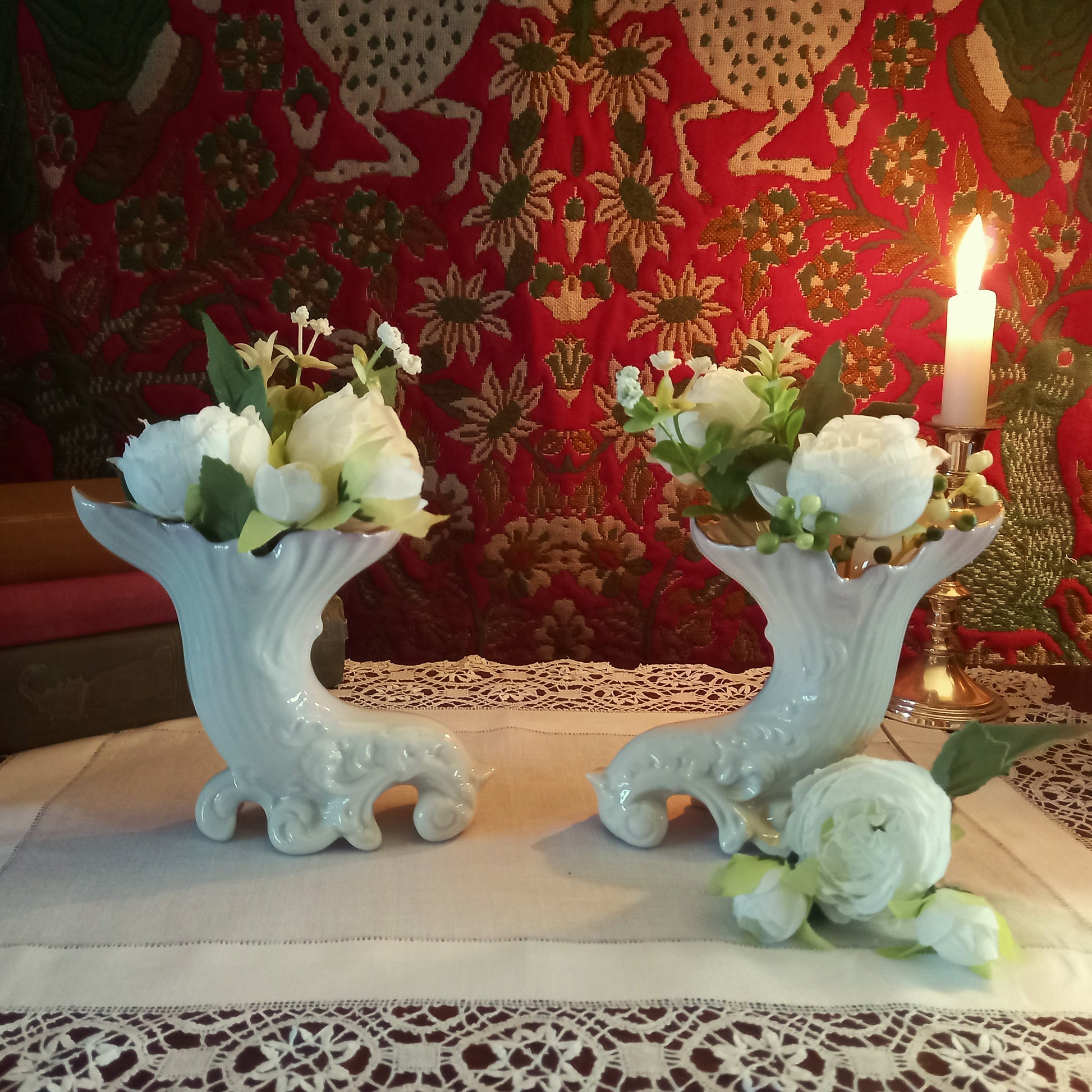A pair of collectible Belleek spill vases in parian porcelain, buffet and tapestry with delicate peony flower display  is shown in an antique setting