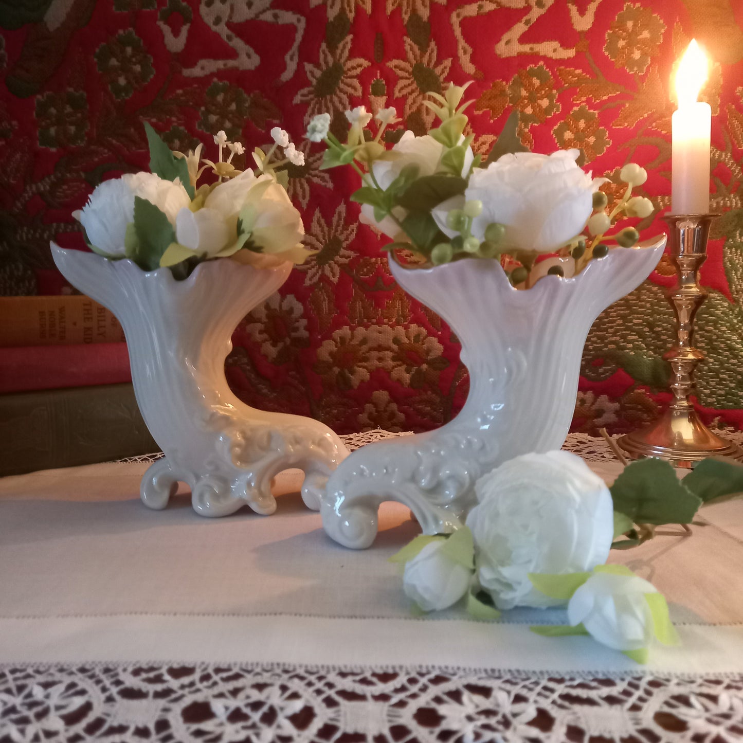 A pair of collectible Belleek spill vases in parian porcelain, buffet and tapestry with delicate peony flower display  is shown in an antique setting