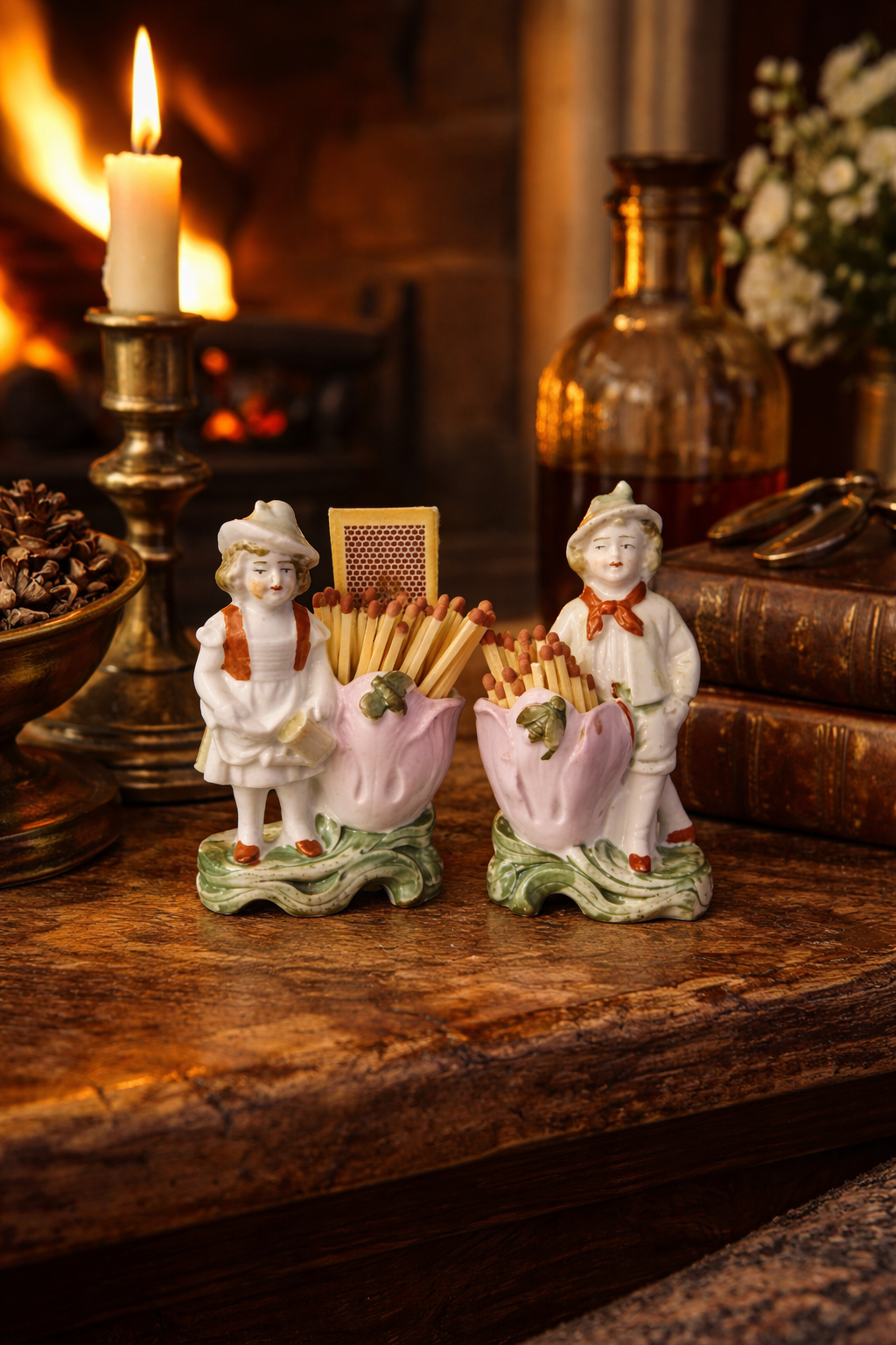 Antique German porcelain figural spill vases repurposed as match holders, styled on a wooden mantel beside a lit candle and fireplace, early 20th century romantic old money decor pair