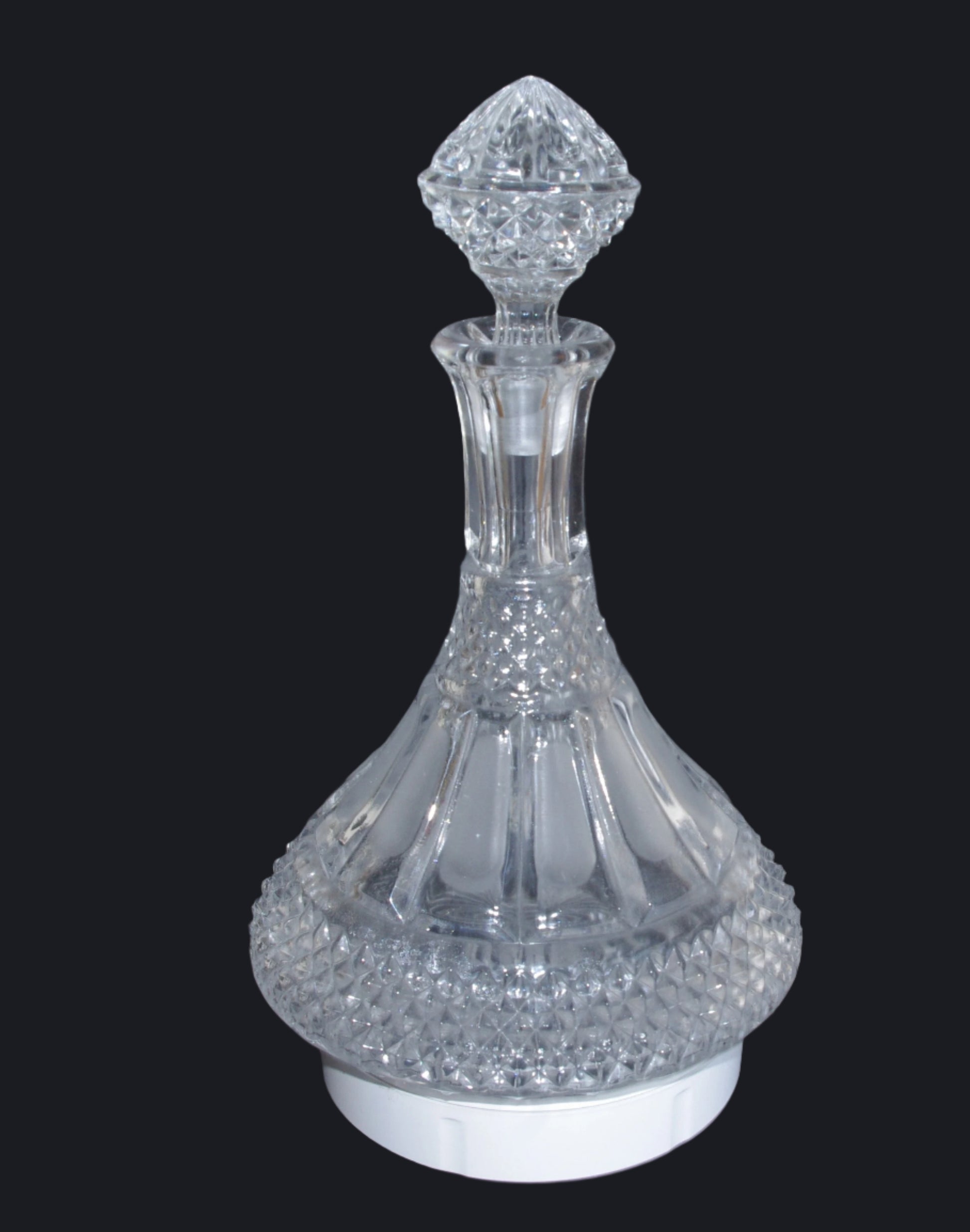 Clear glass decanter with diamond-shaped stopper on a dark background