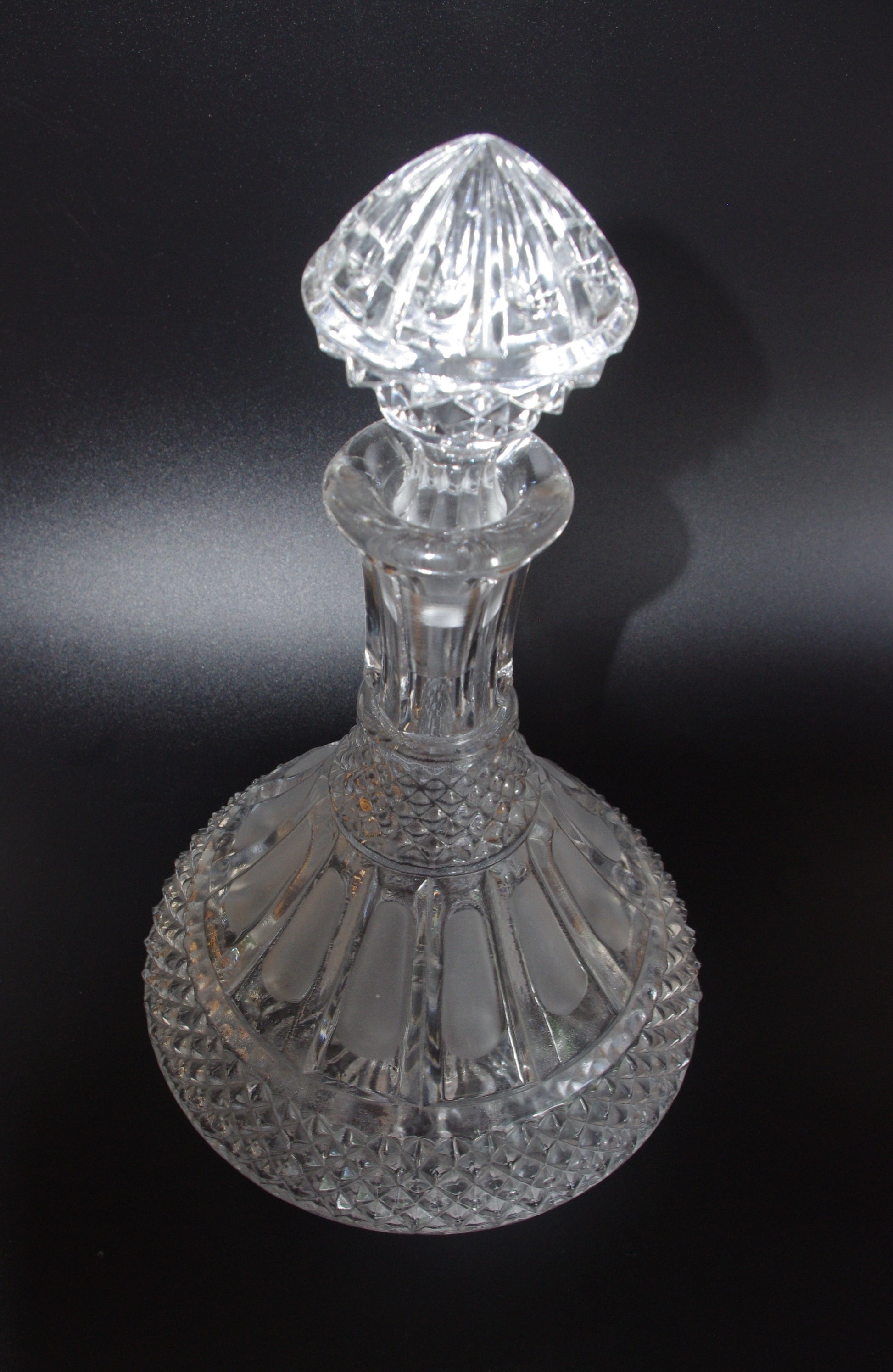 Clear glass decanter with intricate design on a black background