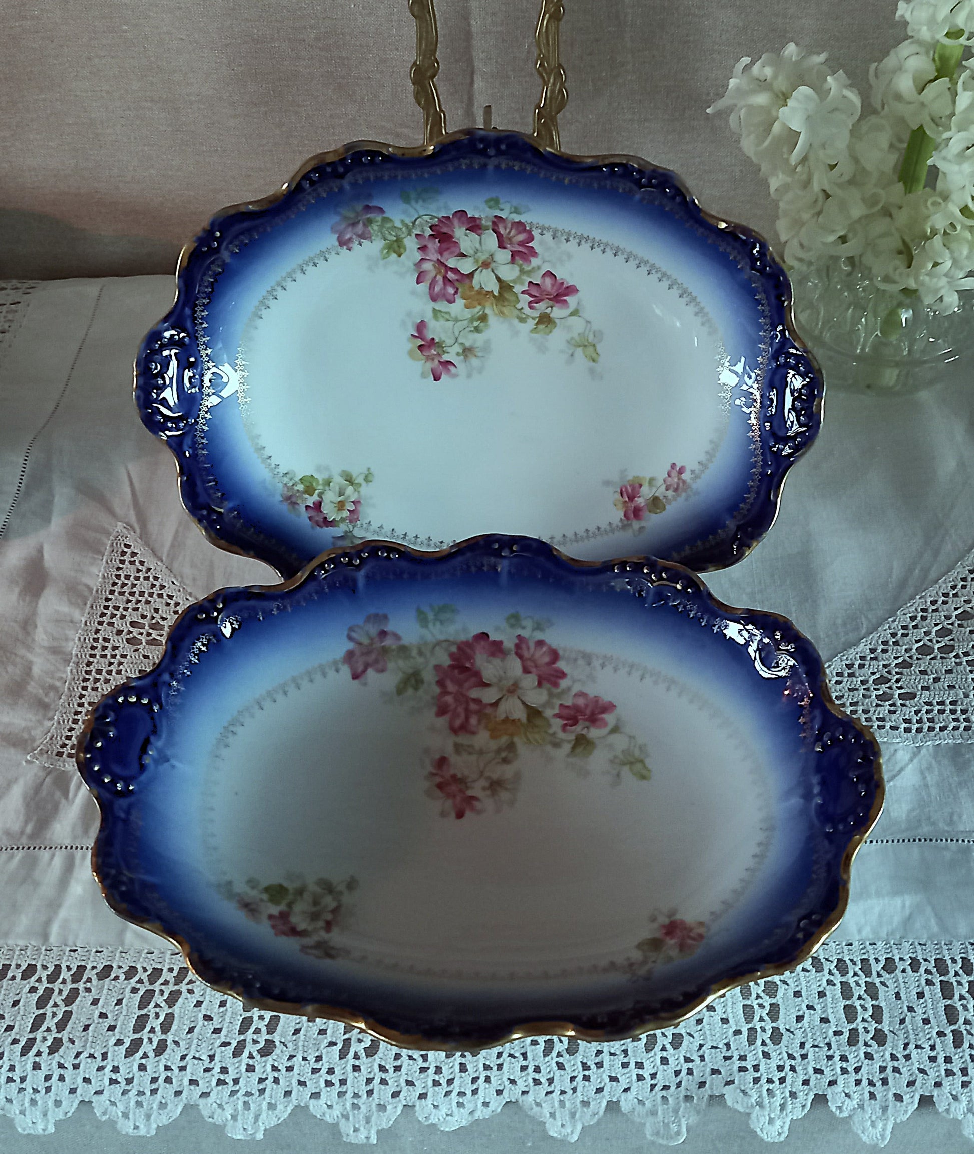 Pair of antique Limoges oval serving dishes, Belle Époque era, cobalt blue and white porcelain with pink floral decoration and gilded scalloped rims.