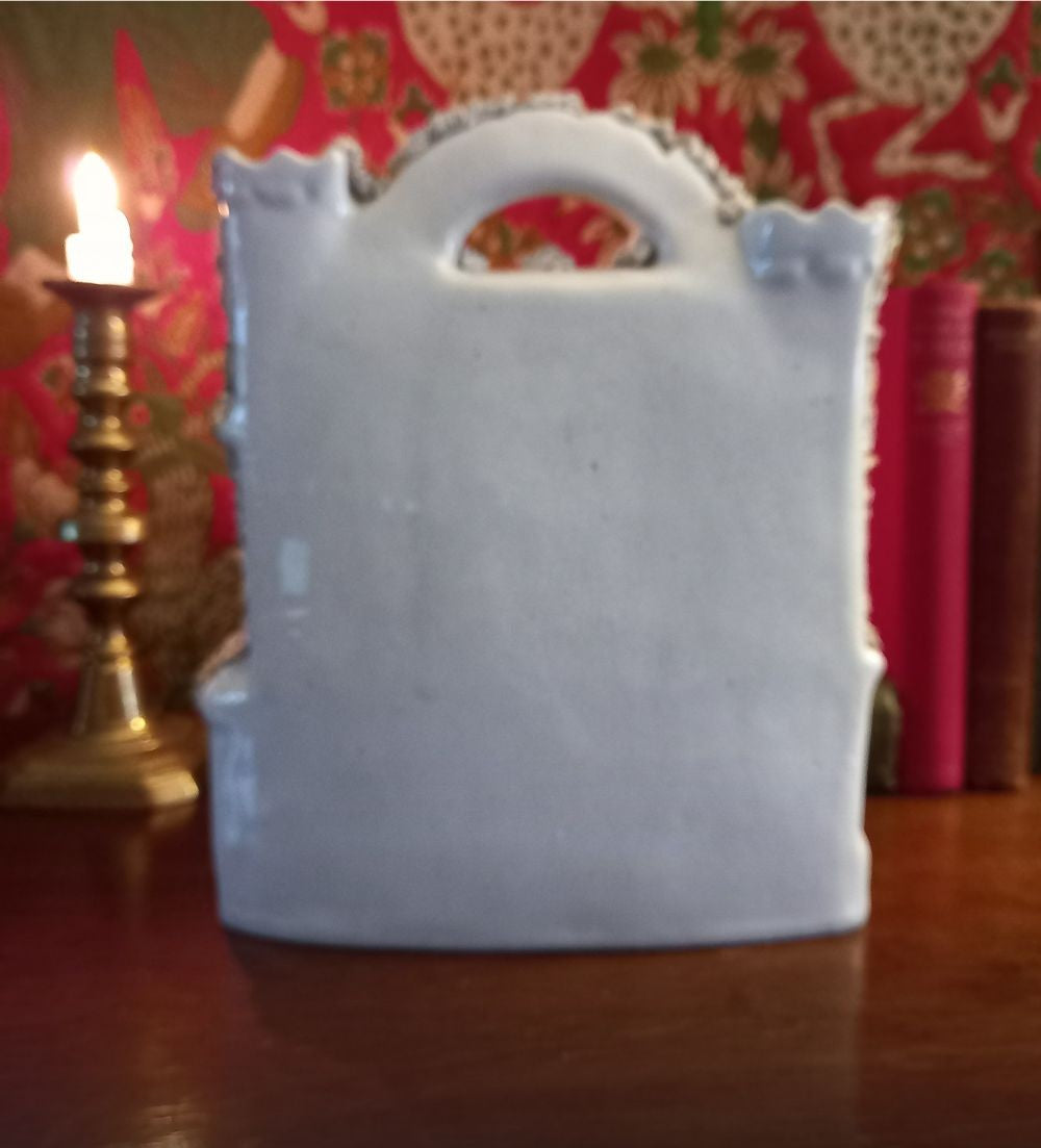 Victorian Staffordshire flatback clock group mantel ornament in glazed earthenware, circa 1850–1875, styled on dark wood library mantel with brass candlestick and antique books rear view