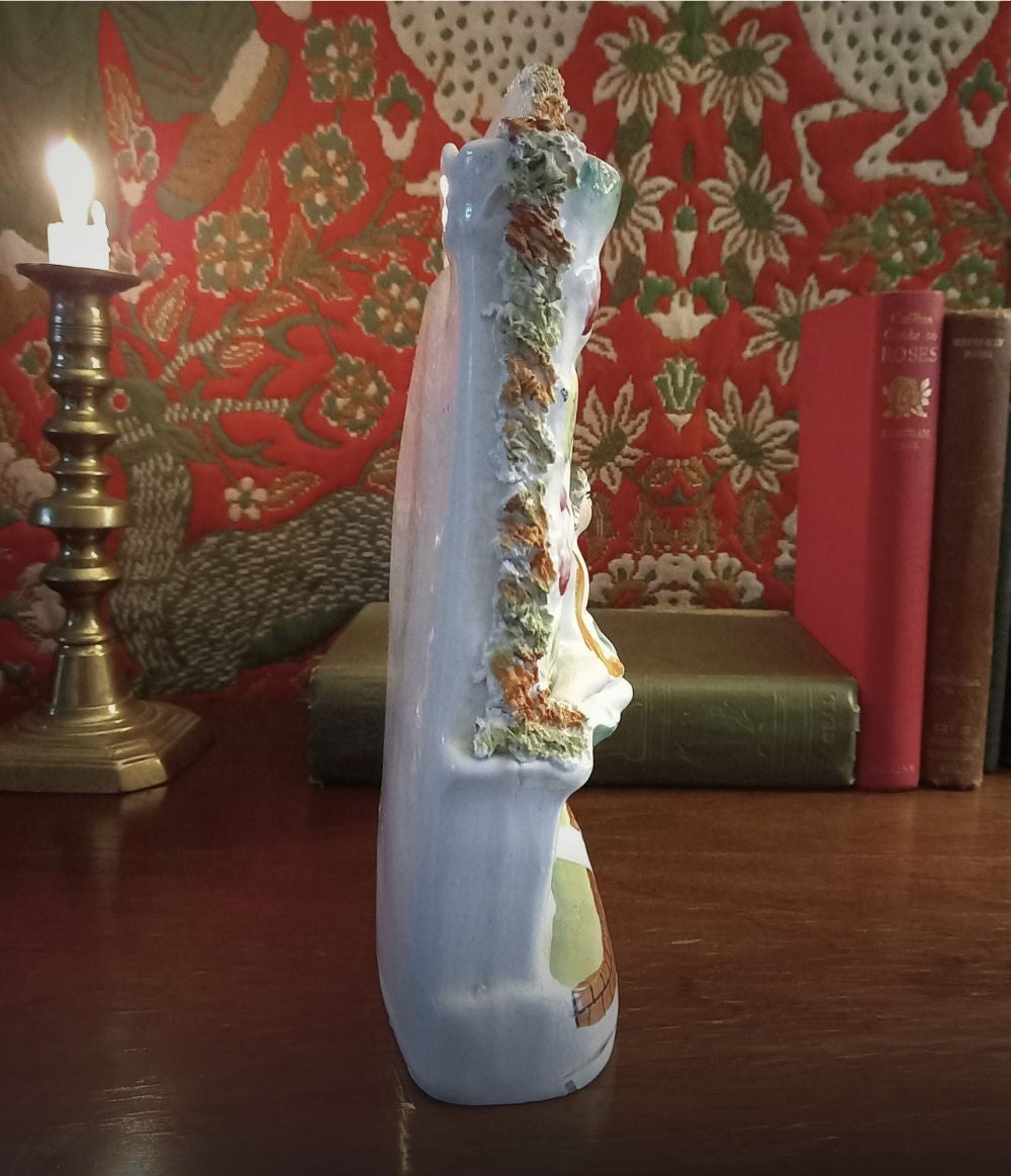 Victorian Staffordshire flatback clock group mantel ornament in glazed earthenware, circa 1850–1875, styled on dark wood library mantel with brass candlestick and antique books side view