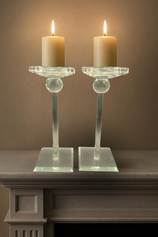 Two lit candles in glass candle holders on a marble surface with a neutral background